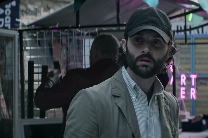 Joe Golberg wears a cap and watched for Marianne in a London market